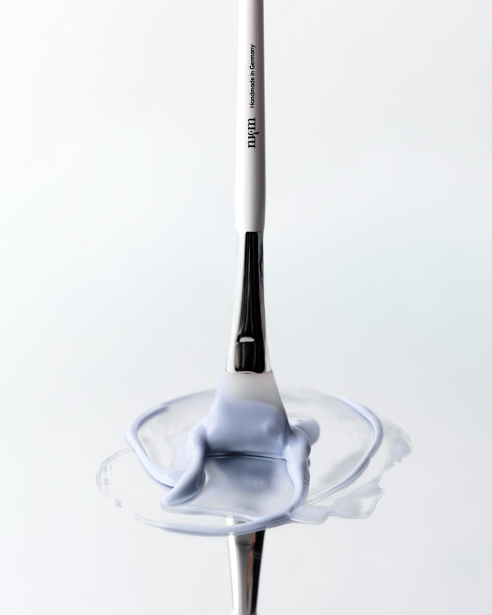 Pinsel mit nkm Logo verstreicht blaue Maske