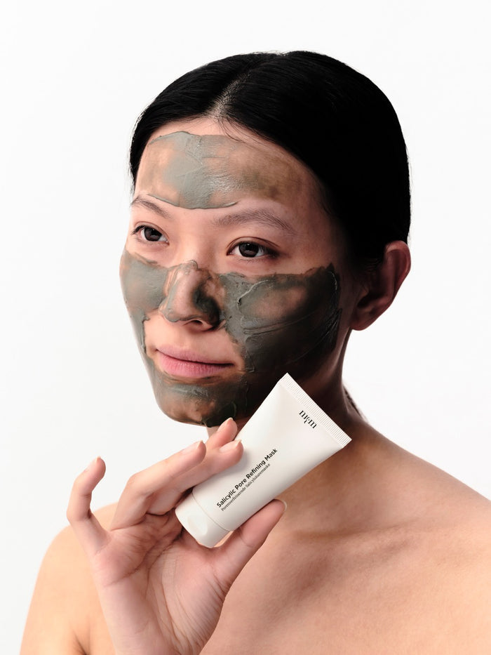 Frau mit Salicylic Pore Refining Mask aufgetragen im Gesicht. Sie hält die Tube in der Hand