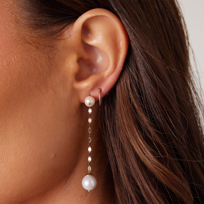 Woman wearring 14k Gold hoop earrings styled with pearl drop earrings