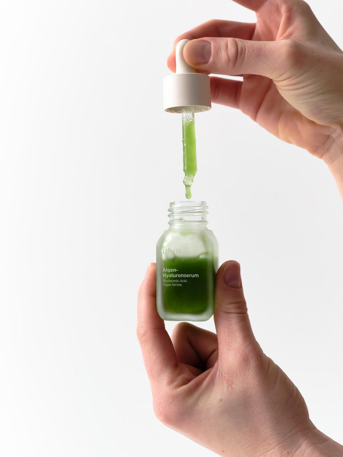 Hand hält Pipette vom Algen-Hyaluronserum von nkm