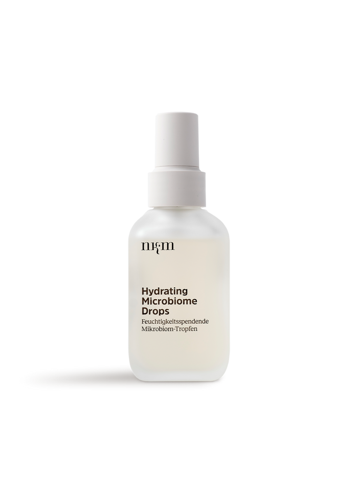 Auf weißem Hintergrund ruht eine mattierte Tropfflasche mit der Aufschrift Hydrating Microbiome Drops von nkm Naturkosmetik München GmbH, ideal für feuchtigkeitsspendendes Liquid und sichtbar hydratisierte Haut.