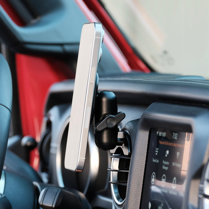Image of Offroam MagSafe-compatible Phone Mount installed securely in Jeep Wrangler 2018-2023 | Gladiator 2019-2023. This premium phone mount installs easily without drilling or glue. High force magnets hold phone on any trail, road, or track. Perfect placement without blocking screens, driver view, or air flow. Fully adjustable positioning.
