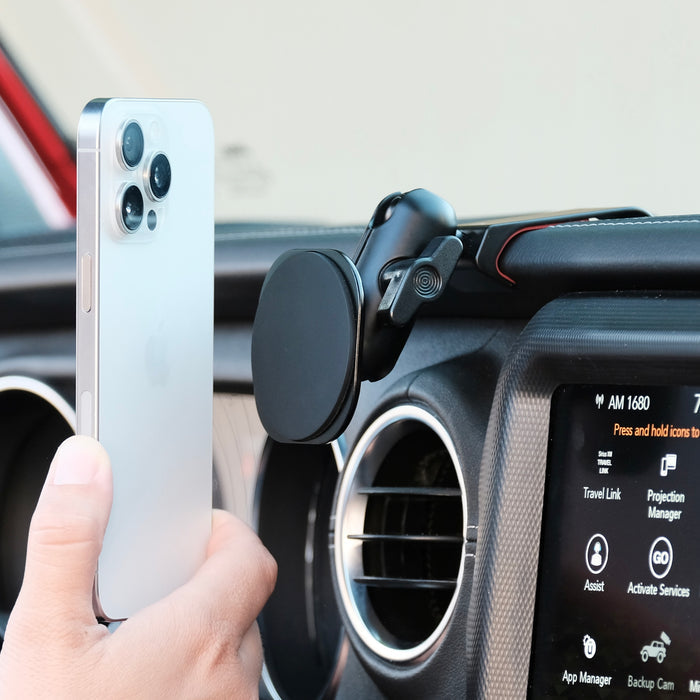 Image of Offroam MagSafe-compatible Phone Mount installed securely in Jeep Wrangler 2018-2023 | Gladiator 2019-2023. This premium phone mount installs easily without drilling or glue. High force magnets hold phone on any trail, road, or track. Perfect placement without blocking screens, driver view, or air flow. Fully adjustable positioning.