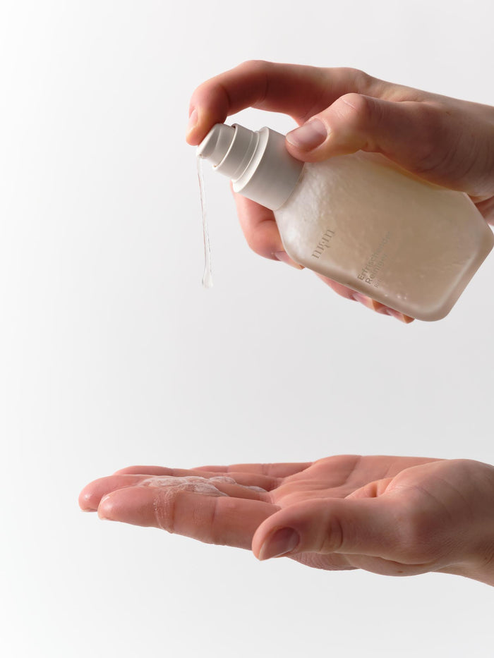 Eine Hand verteilt Erfrischender Reiniger Neu von nkm Naturkosmetik München GmbH auf einer anderen Handfläche vor weißem Hintergrund - ideal für reife Haut und trockene Haut.