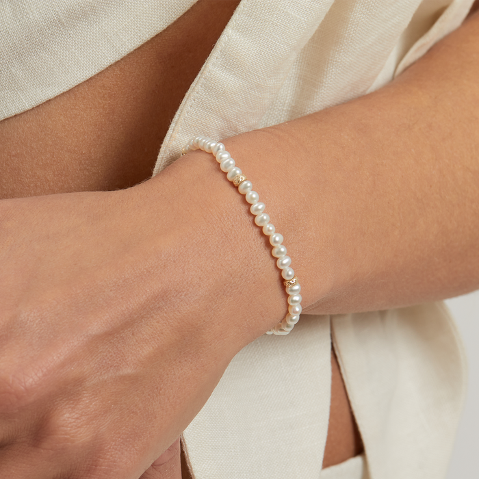 14K yellow gold pearl beaded bracelet worn on wrist close up freshwater pearl stretch bracelet fine jewelry