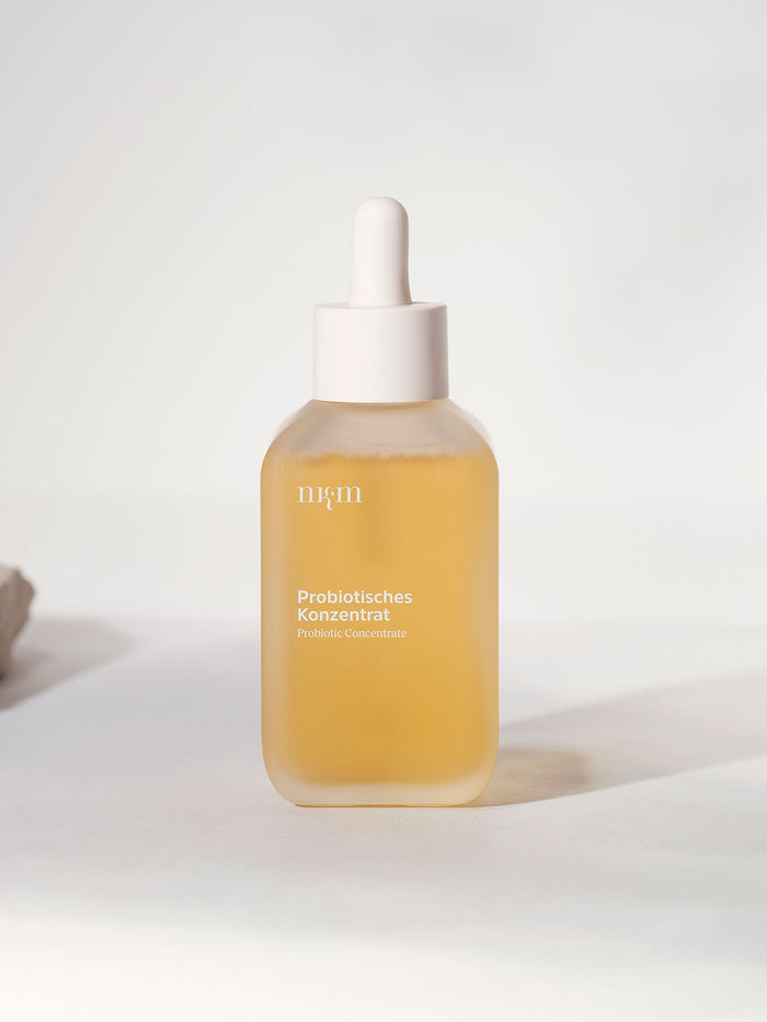 In einer gläsernen Tropfflasche der nkm Naturkosmetik München GmbH mit der Aufschrift Probiotisches Konzentrat befindet sich ein hellgelbes, feuchtigkeitsspendendes Konzentrat zur Unterstützung der Hautbarriere.