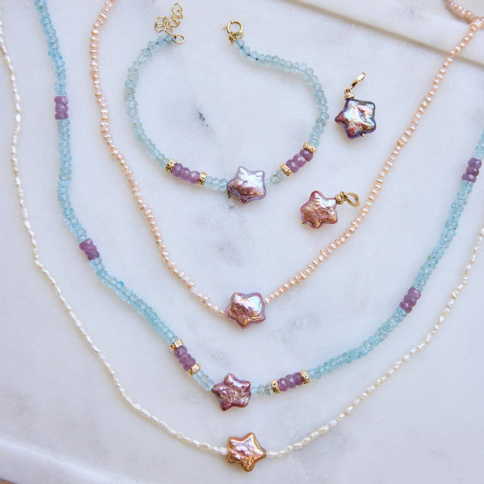 A collection of necklaces, charms, and bracelets with star shaped baroque pearls, mini pearl strands, aquamarine and pink sapphire beads, and 14K solid gold.