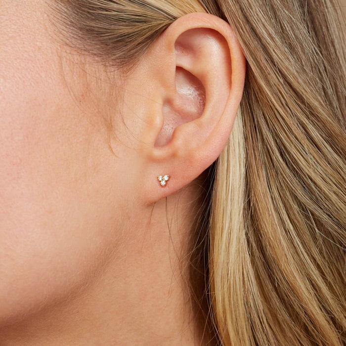 14k solid gold trio diamond stud earrings on model's ear.