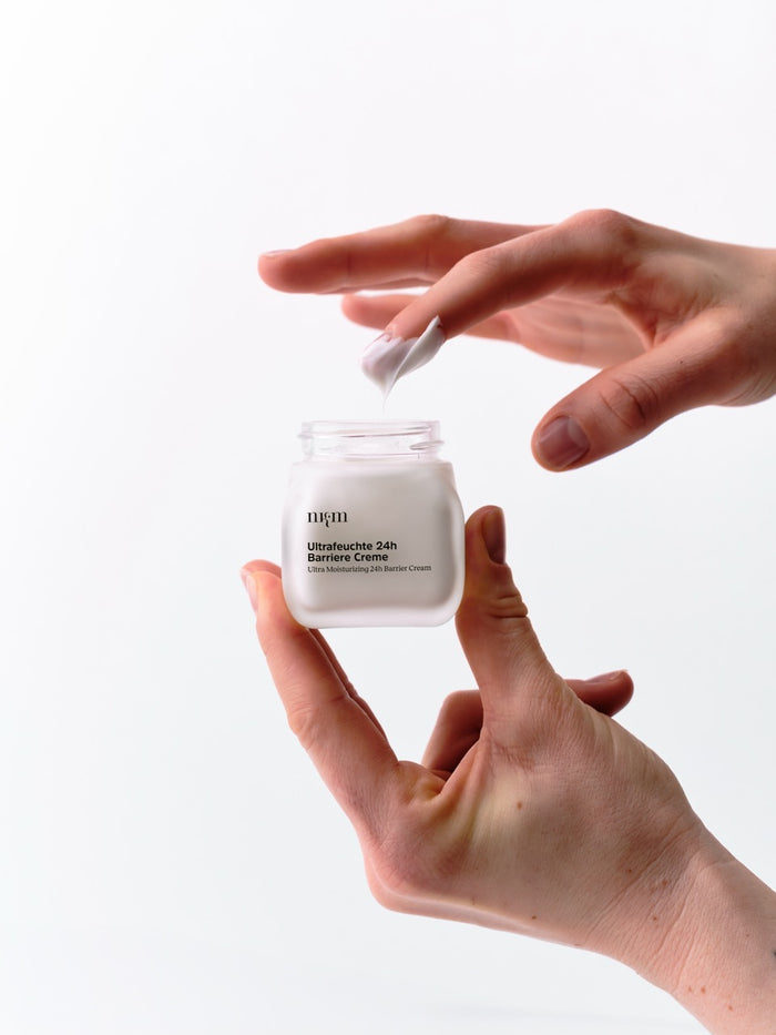Finger tunkt in die Ultrafeuchte 24h Barriere Creme von nkm