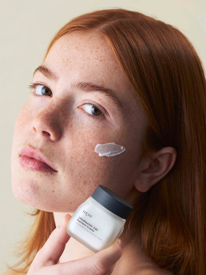 Eine Frau, die die Ultrafeuchte 24h Barriere Creme in der Hand hält