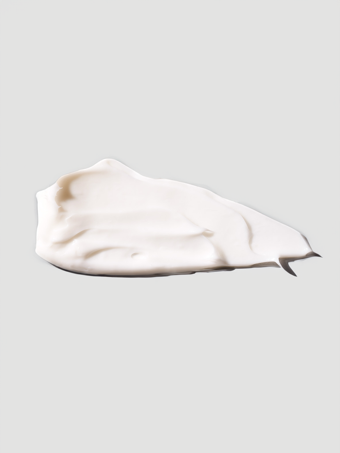 Ein Abstrich der weißen Ultrafeuchte 24h Barriere Creme der nkm Naturkosmetik München GmbH, die Niacinamid und Ceramiden enthält, auf hellgrauem Grund.