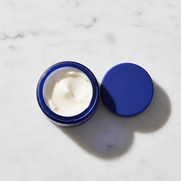 Ursa Major Golden Hour Recovery Cream blue jar open showing cream texture on white marble